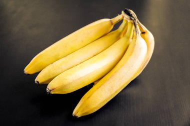 Siyah ahşap bir masada bir avuç organik muz.