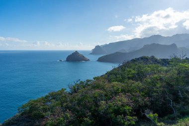 Marquesas Adaları 'ndaki Nuku Hiva' daki Taiohae Körfezi 'nin engebeli uçurumları parlak bir gökyüzünün altından çıkan küçük kayalık adalarla derin mavi Pasifik Okyanusu' na düşer. Fransız Polinezyası