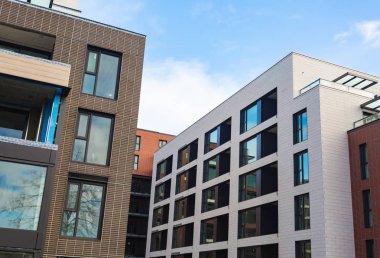 Çok katlı modern ev yakın çekim. Tuğla, windows, cam gökyüzünde yansımaları. Gündüz, güneş. Modern Daire Kompleksi İnşaatı