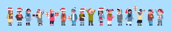 Mix wyścigu osób Grupa noszenia zimowe ubrania czerwony kapelusz przytrzymaj prezent pole obecne merry christmas wakacje szczęśliwego nowego roku koncepcja pełnej długości płaskiej, poziomej transparent — Wektor stockowy