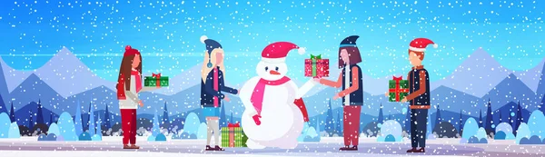 La gente sostiene envuelto regalo caja regalo para muñeco de nieve feliz Navidad feliz año nuevo vacaciones concepto invierno montañas bosque paisaje fondo plano horizontal — Vector de stock