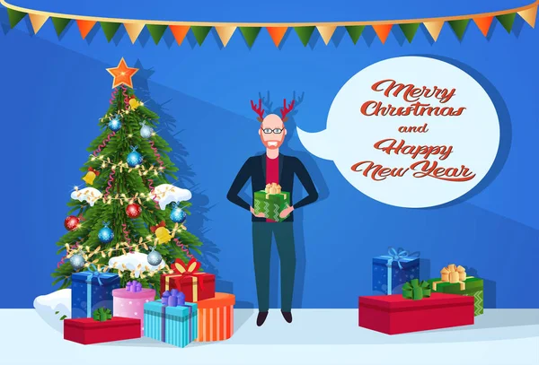 Muž v Jelení rohy drží dárkové krabice chat bubliny jedle strom šťastný nový rok veselé vánoční koncept rovinnou a vodorovnou nápis — Stockový vektor