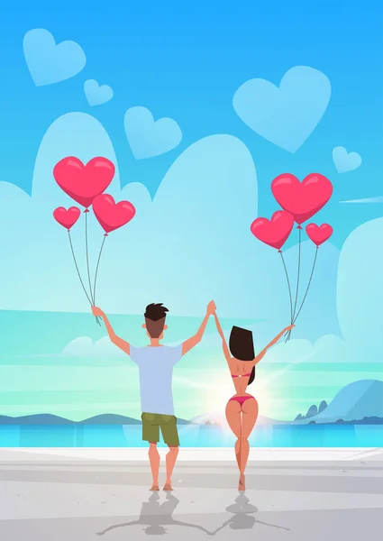 Vista trasera pareja sosteniendo rosa corazón forma aire globos mar océano playa verano vacaciones concepto hombre mujer en amor sobre puesta de sol mar fondo longitud completa vertical plana — Vector de stock