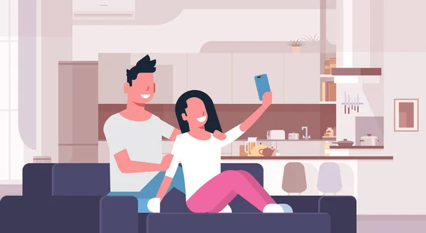 Paret tar selfie foto på smart telefon man kvinna sitter på soffan unga lyckliga älskande modernt kök interiör manliga kvinnliga seriefigurer platt horisontellt — Stock vektor