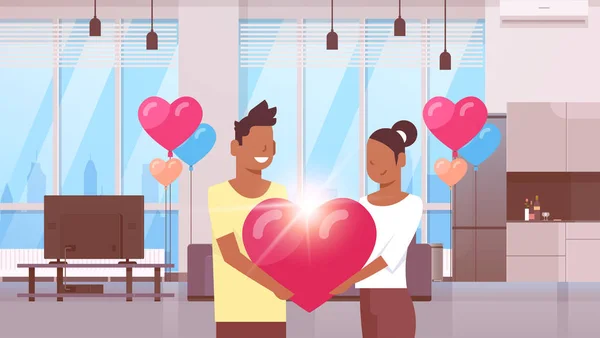 Pareja sosteniendo rosa corazón forma feliz día de San Valentín concepto africano americano hombre mujer amantes de pie juntos moderno apartamento interior colorido aire globos plana horizontal — Vector de stock