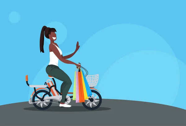 Femme vélo portant des sacs en papier colorés achète concept de shopping afro-américaine fille équitation vélo personnage de bande dessinée femme pleine longueur horizontale plat — Image vectorielle