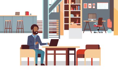 İşyeri yaratıcı office iş merkezi iç yatay tam uzunluğu birlikte oturan kulaklıklar Afrikalı-Amerikalı işadamı ile müzik dizüstü kullanan adam