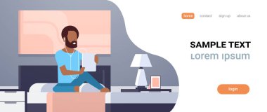 adam dinleme ses kaseti kulaklık Afrika americn adam yatak modern ev yatak odası iç erkek karakter tam uzunlukta düz yatay kopya alanı üzerinde oturan tablet kullanma yoluyla