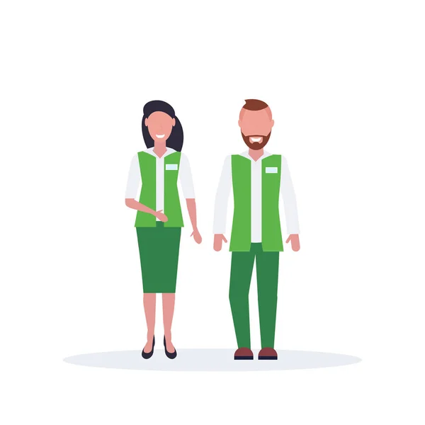 Casal homem mulher supermercado empregados pé juntos vendedor e vendedora em verde uniforme feliz masculino feminino personagens de desenhos animados comprimento total plana isolado — Vetor de Stock