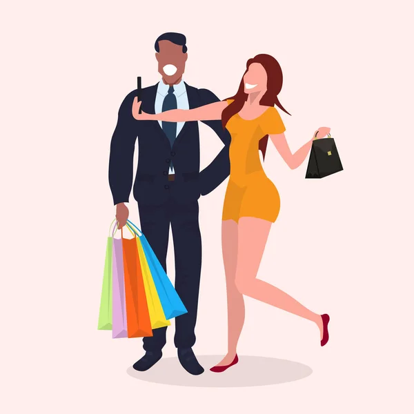 Mix race couple taking selfie photo on smartphone camera girl holding handbag african man with shopping bags standing together posing and smiling cartoon characters full length flat — Stock Vector