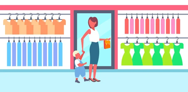 Γυναίκα με το γιο του μωρού επιλέγοντας νέα ρούχα νεαρή μητέρα και το μικρό αγόρι να περπατά μεγάλη μόδα κατάστημα boutique σύγχρονο εμπορικό εσωτερικό οριζόντιο πλήρες μήκος — Διανυσματικό Αρχείο