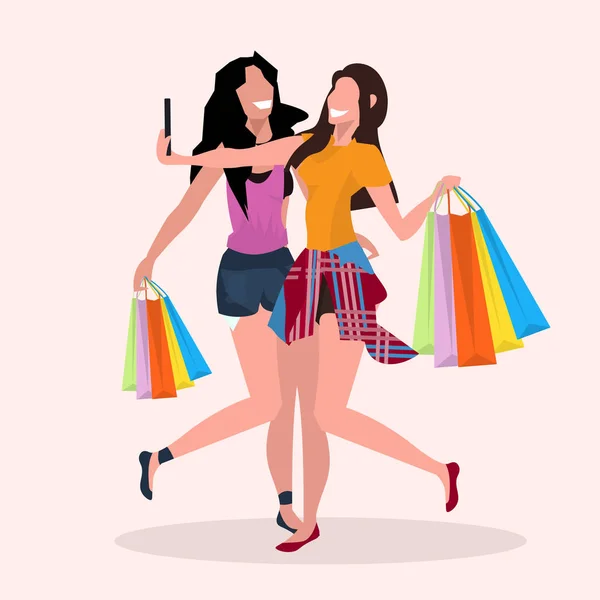 Δύο γυναίκες λήψη selfie φωτογραφία στο smartphone κάμερα κορίτσια με πολύχρωμες τσάντες αγορών που παρουσιάζουν και χαμογελαστός μεγάλη πώληση έννοια θηλυκό καρτούν χαρακτήρες πλήρους μήκους επίπεδη — Διανυσματικό Αρχείο