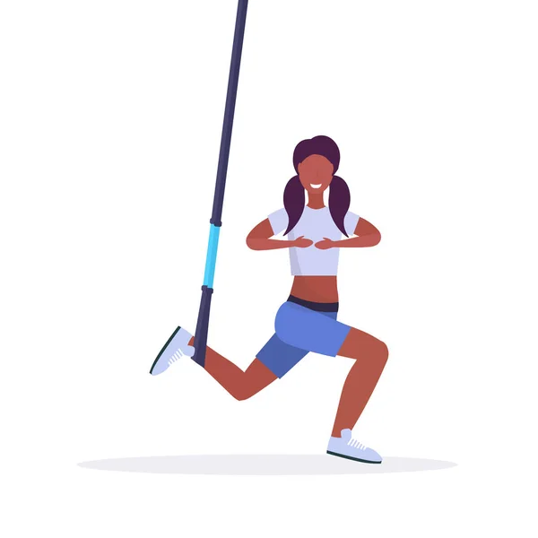 Sportowy kobieta robi przysiady ćwiczenia z zawieszenia taśmy elastycznej liny african american dziewczynka fitness szkolenia w siłownię crossfit cardio workout koncepcja płaskie białe tło pełnej długości — Wektor stockowy