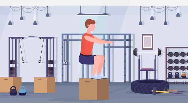 Sportovní člověk dělá box squat cvičení chlap skákání, cvičit v tělocvičně crossfit zdravého životního stylu koncept moderní fitness club studio interiéru horizontální — Stockový vektor