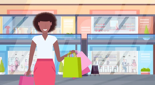 Mujer sosteniendo coloridas bolsas de compras concepto de gran venta chica afroamericana caminando moderno centro comercial con ropa y cafeterías supermercado interior horizontal retrato plano — Vector de stock