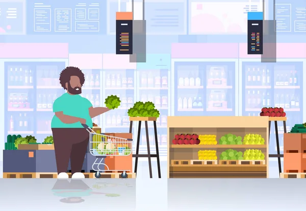 Fat παχύσαρκος άνθρωπος με καλάθι ψώνια επιλογή λαχανικά και φρούτα υπέρβαρων Αφρικανός Αμερικανός τύπος σούπερ μάρκετ βάρος πελάτη έννοια παντοπωλείο κατάστημα εσωτερικό οριζόντια πλήρες μήκος — Διανυσματικό Αρχείο