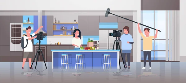 Operadores que utilizan la cámara de vídeo de grabación de alimentos blogger mujer preparando sabrosos platos videógrafos utilizando equipo profesional cocina blog producción de películas concepto cocina interior horizontal — Vector de stock