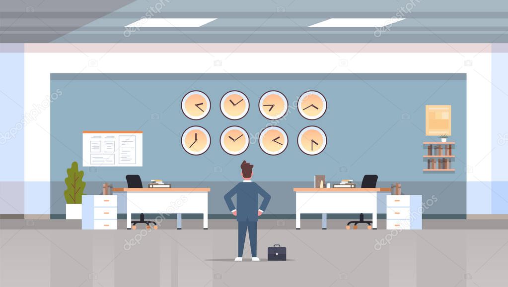 businessman looking on wall with clocks of different cities time management deadline concept modern workspace office interior horizontal rear view male character full length