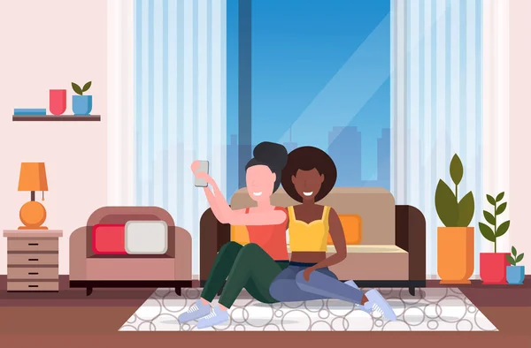 Zwei Frauen Selfie-Foto auf Smartphone-Kamera Mix Rennen Mädchen sitzen auf dem Boden in der Nähe der Couch modernes Wohnzimmer Interieur afrikanisch-amerikanischen weiblichen Cartoon-Figuren volle Länge horizontal — Stockvektor