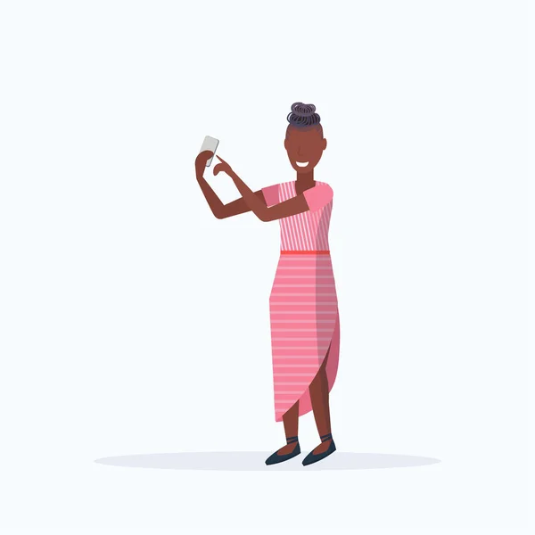 Mulher tirar foto selfie no smartphone câmera afro-americana personagem de desenho animado do sexo feminino posando no fundo branco plana comprimento total — Vetor de Stock