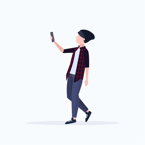 Homem tirar foto selfie no smartphone câmera casual masculino personagem cartoon em chapéu posando no fundo branco plana comprimento total — Vetor de Stock