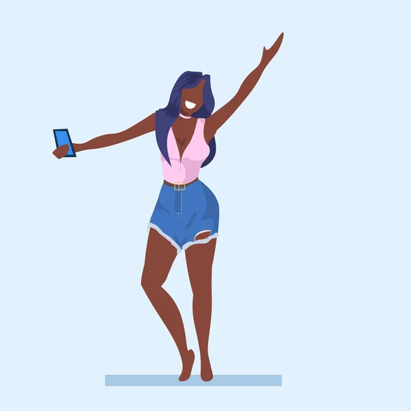 Mulher casual tirar foto selfie no smartphone câmera jovem afro-americano menina levantando mão personagem de desenho animado feminino posando plana comprimento total — Vetor de Stock