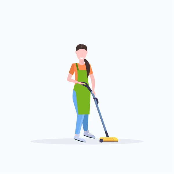 Vrouw in schort met behulp van stofzuiger vrouwelijke conciërge schoonmaken service vloerverzorging concept platte volledige lengte witte achtergrond — Stockvector