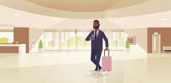 Homem de negócios com bagagem moderna recepção área afro-americana homem de negócios segurando mala cara de pé no lobby contemporâneo hotel salão interior horizontal comprimento total — Vetor de Stock