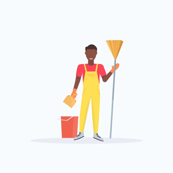 Άνθρωπος κρατώντας σκούπα Αφρικανός Αμερικάνος καθαριστής σκούπισμα δαπέδου καθαρισμός υπηρεσία καθαριότητα ιδέα πλήρους μήκους επίπεδη λευκό φόντο — Διανυσματικό Αρχείο