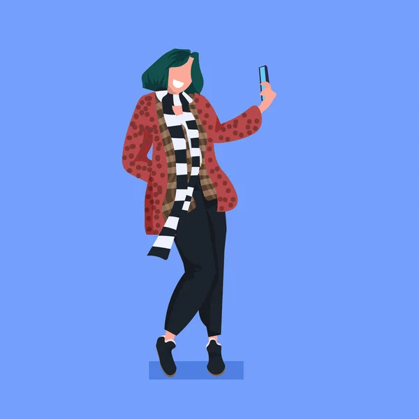 Mujer tomando foto selfie en el teléfono inteligente cámara casual personaje de dibujos animados femeninos de pie pose plana de longitud completa fondo azul — Vector de stock