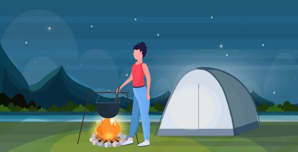 Žena hiker vaření jídla dívka příprava potravin v bowler vaření pot na campfire hiking koncept cestovatel na túry stan camping noc krajina na pozadí plné délky byt horizontální — Stockový vektor