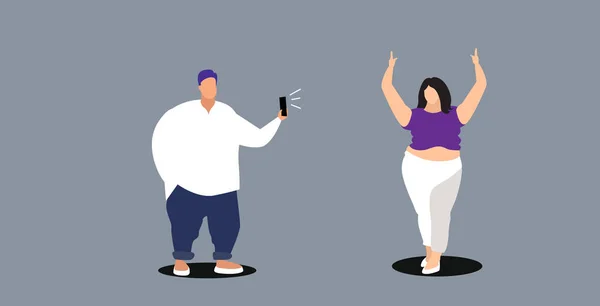 Hombre gordo usando smartphone cámara chico tomando foto de la mujer joven con sobrepeso modelo de moda disparar concepto de dibujo garabato horizontal de longitud completa — Archivo Imágenes Vectoriales