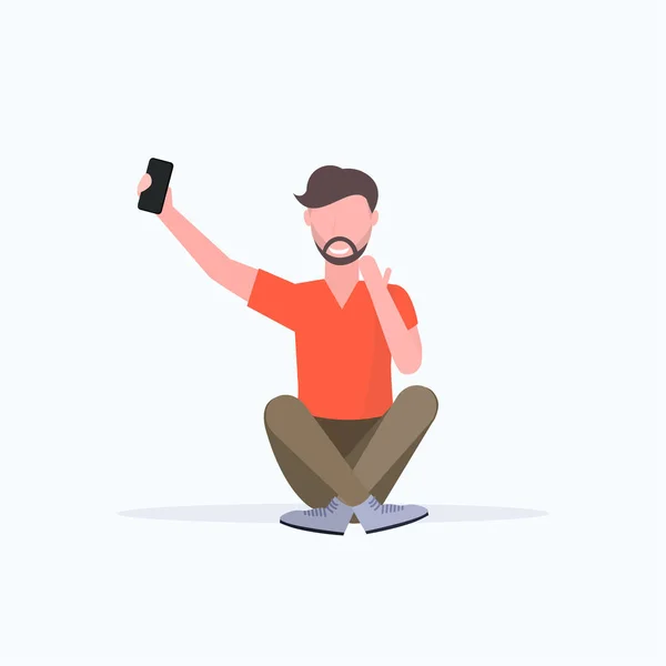 Мужчина делает селфи фото на смартфоне камера случайный мужчина персонаж мультфильма сидя позируя белый фон плоский всю длину — стоковый вектор