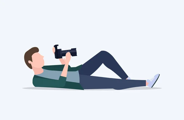 Fotógrafo profissional tirar foto com homem câmera digital deitado e atirando personagem cartoon masculino de comprimento total plana ilustração vetorial horizontal —  Vetores de Stock