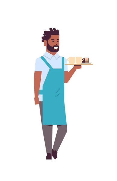 Camarero profesional sosteniendo café y pastel en bandeja hombre afroamericano trabajador de restaurante en delantal sirviendo concepto de comida plana de longitud completa fondo blanco vertical — Vector de stock