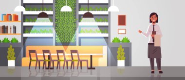 profesyonel garson tutarak menü sıcak misafirperverliği modern kafe iç düz tam uzunlukta yatay gösteren apron rahat restoran kadın işçi karşılama