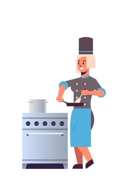 Chef profesional femenino utilizando sartén revolviendo comida mujer restaurante cocina trabajador en uniforme de pie cerca de la estufa concepto de cocina plana de longitud completa vertical — Archivo Imágenes Vectoriales