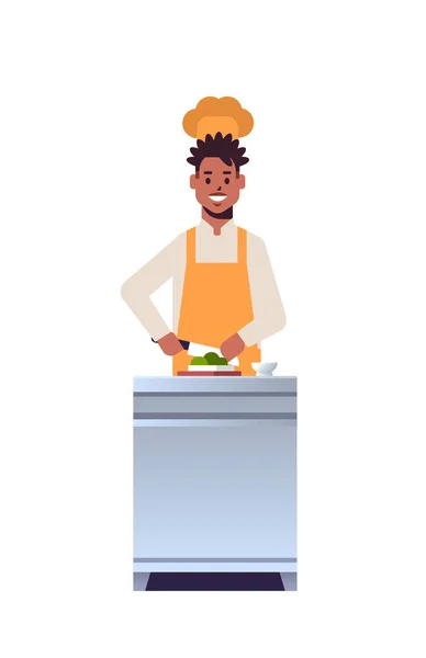 Chef profesional masculino cocinero picando verduras frescas en tabla de tallar hombre afroamericano trabajador de restaurante en uniforme preparando ensalada cocina concepto de comida plana de longitud completa vertical — Vector de stock