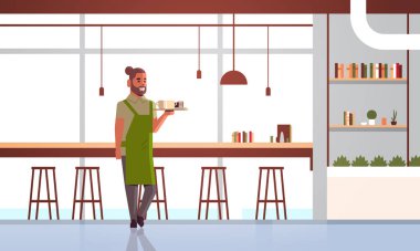 tepsi adam kafe işçi barista üzerinde kahve ve kek taşıyan garson tatlı modern kafeterya iç tam uzunlukta yatay ile cappuccino iki bardak tutan apron