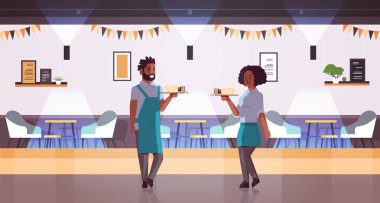 garsonlar çift tepsi de kahve ve kek taşıyan afrikalı-amerikalı kadın erkek kafe işçileri barista önlük tatlılar modern kafeterya iç tam uzunlukta yatay ile kapuçino bardak tutan