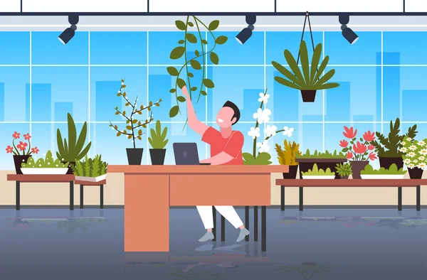 Hombre de negocios sentado en un lugar de trabajo cómodo con plantas en maceta ambiente doméstico concepto de oficina verde — Archivo Imágenes Vectoriales