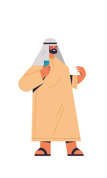 Árabe homem em roupas tradicionais árabe empresário usando smartphone masculino desenho animado personagem em pé pose — Vetor de Stock