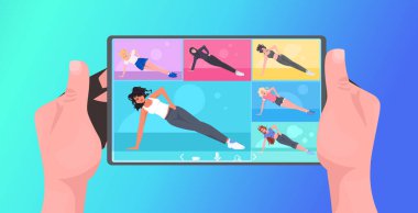 Irkçı kadınların yoga egzersizlerini tablet ekranda, sağlıklı yaşam tarzı konseptini eğiterek yapıyorlar.