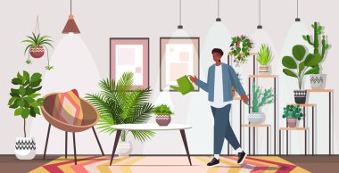 Sulama kabı olan bir adam ev bitkileriyle ilgilenir oturma odası ya da bahçe içi ile.