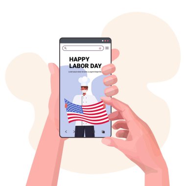 Amerikan bayrağı taşıyan akıllı telefon ekranında üniformalı bir şef mutlu işçi bayramı kutlaması konseptini taşıyor.