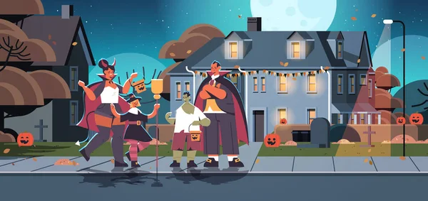 Famille en costumes différents marche dans la ville astuce ou traiter heureux concept de célébration d'Halloween — Image vectorielle