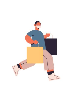 Koruyucu maskeli genç adam alışveriş çantalarıyla koşuyor. Kara Cuma. Büyük indirim Coronavirüs karantina konsepti.