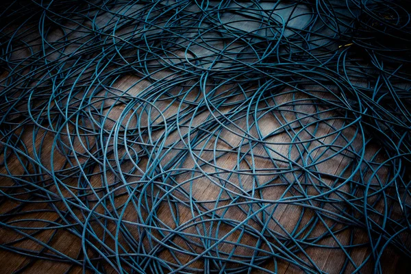 Network chaos of colorful cables on the wooden floor.