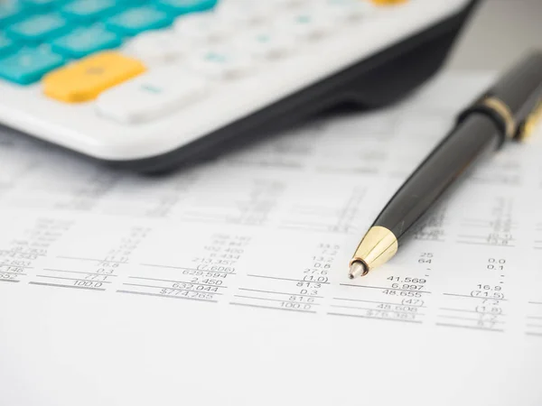 A close-up shot of a calculator.  A printed balance sheet and a pen are also visible.