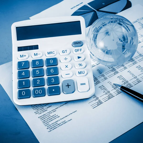 A close-up shot of a calculator.  A printed balance sheet and a pen are also visible.